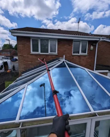 Cleaning a conservatory roof with professional equipment to remove dirt, moss, and debris.